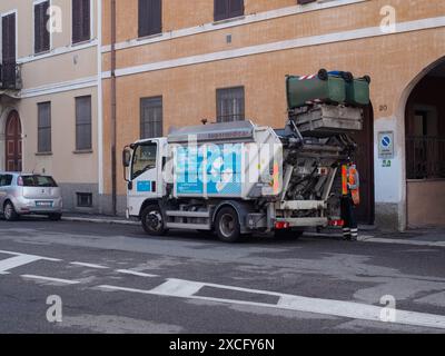 Cremona, Italien - 10. Juni 2024 Müllwagen sammelt Mülltonnen mit einem Sanitärangehörigen, der in einer städtischen Straße wartet Stockfoto