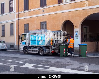 Cremona, Italien - 10. Juni 2024 Müllmann mit orangefarbener Weste sammelt Mülltonnen mit LKW auf der Straße Stockfoto