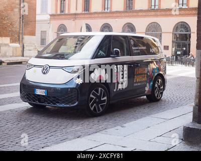 Cremona, Italien - 10. Juni 2024 Elektrowagen von Volkswagen, geschmückt mit Blumen, die die Kraft der Blume fördern, geparkt auf einer kopfsteingepflasterten Straße, die modern präsentiert Stockfoto