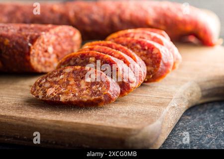 In Scheiben geschnittene geräucherte Salami-Wurst auf einem hölzernen Schneidebrett. Stockfoto