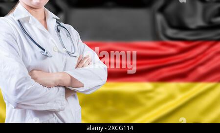 Ärztin mit gekreuzten Armen mit deutscher Flagge im Hintergrund. Gesundheitskonzept mit Deutschland-Flagge im Hintergrund Stockfoto