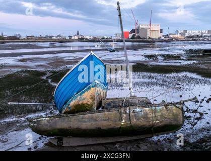 Gerammte Boote auf Schlamm bei Barrow in Furness am Walney Channel mit einer BAE U-Boot-Fabrik im Hintergrund in der Abenddämmerung Stockfoto