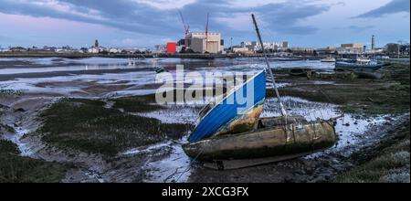 Gerammte Boote auf Schlamm bei Barrow in Furness am Walney Channel mit einer BAE U-Boot-Fabrik im Hintergrund in der Abenddämmerung Stockfoto