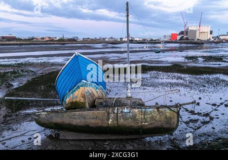 Gerammte Boote auf Schlamm bei Barrow in Furness am Walney Channel mit einer BAE U-Boot-Fabrik im Hintergrund in der Abenddämmerung Stockfoto