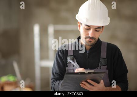 Porträt eines Bauarbeiters, der sich Notizen auf die Zwischenablage in einem Haus macht Stockfoto