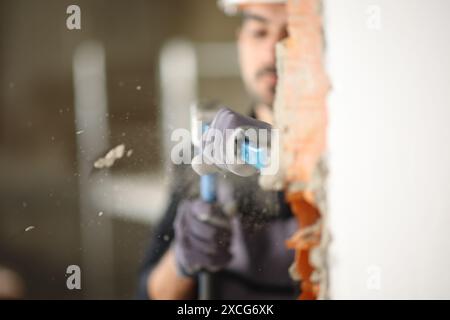 Bauarbeiter, der in einem reformierten Haus mit Steilhang und Hammer eine Mauer abriss Stockfoto