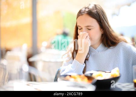 Kranker Restaurantkunde, der auf einer Terrasse auf ein Taschentuch bläst Stockfoto