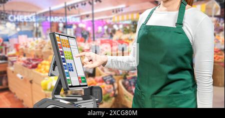 Aktive asiatische Verkäufer tragen grüne Schürze und grüne Kappe und lächeln mit POS-Terminal oder Kassenschalter Stockfoto