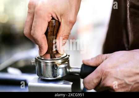 Der Barista streichelt den Kaffeesatz mit einem Manipulator in den Portafilter. Stockfoto