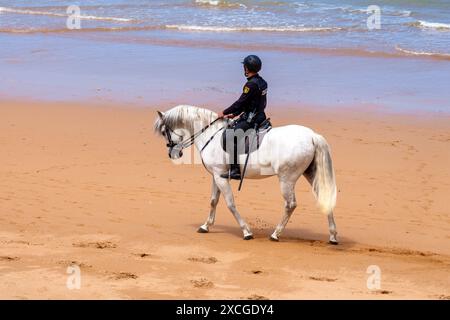 Gijon, Spanien - 24. Mai 2024: Streife der spanischen Nationalpolizei am Strand. Ein uniformierter Offizier zu Pferd kontrolliert das Küstengebiet i Stockfoto