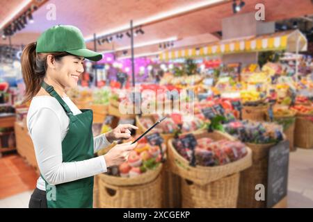 Asiatische Verkäufer tragen grüne Schürze und grüne Kappe, die auf dem Markt lächelnd sind Stockfoto