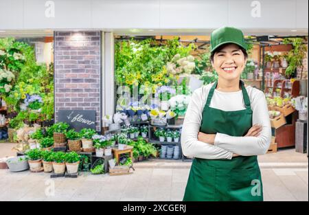 Asiatische Verkäufer tragen grüne Schürze und grüne Kappe, die auf dem Markt lächelnd sind Stockfoto