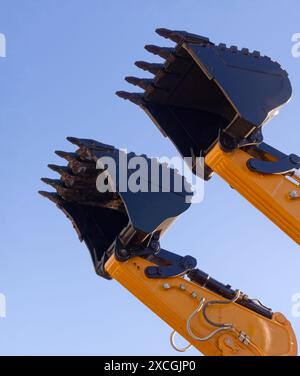 Schaufel und Hydraulikarm eines Baggers, isoliert auf klarem blauem Himmel Hintergrund, perspektivische Aufnahme aus flachem Winkel. Stockfoto