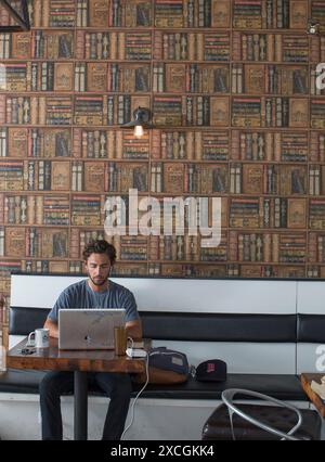 Ein Mann sitzt in einem Café und arbeitet an seinem Laptop. Stockfoto