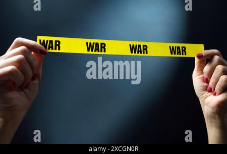 Warnende Hände Halten Gelbes Klebeband Mit Kriegstext Als Symbol Für Sicherheit Und Konfliktaufhalt. Konzept Von Invasion Und Krieg Stockfoto