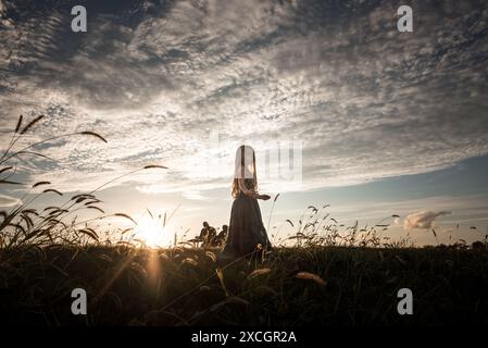 Schönes Mädchen, das in langem Kleid unter blauem Himmel spielt Stockfoto