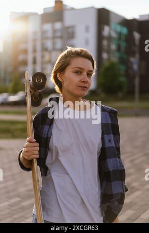 Junge Frau mit Skateboard in der Stadt. Stockfoto