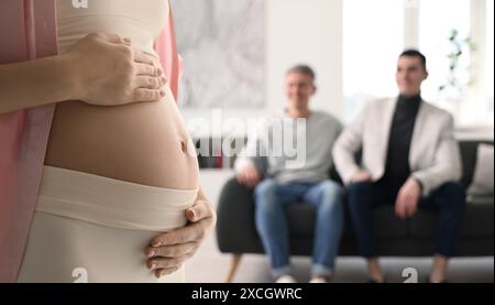 Schwangere Leihmutter und glückliches Schwulenpaar zu Hause, selektiver Fokus Stockfoto