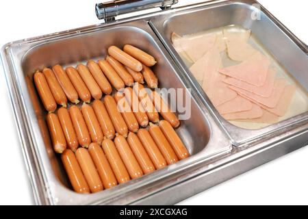 Gestanzte Hähnchenschinken und Sauage in Edelstahl-Küchenwärmer und Gericht auf weiß isoliert. Stockfoto