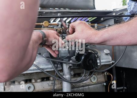 Mechaniker für Rennwagen, der mit einer Fühlerlehre an den elektrischen Punkten im Verteilerkappe arbeitet und diese justiert. Stockfoto