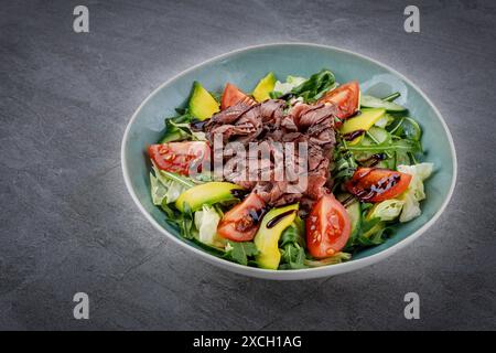 Leckerer Salat - gebratene Kalbslende, Avocado, gekochte Eier und frisches Gemüse auf Steintisch Stockfoto