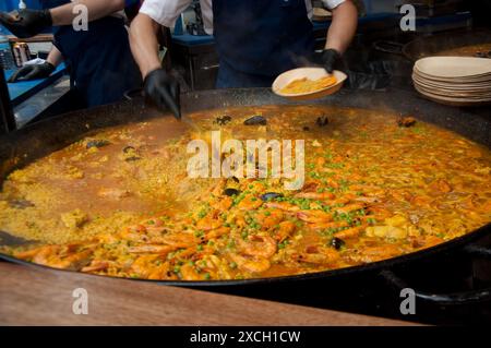 Paella vorbereiten, Borough Market, Bermondsey, Southwark, London, UK - Paella; spanische Delikatesse; Garnelen; Erbsen; Reis; Stockfoto