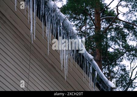 Wunderschöne riesige Eiszapfen hängen vom Dach des Gebäudes. Stockfoto