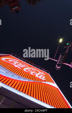 Blick auf das rote neonfarbene Kings Cross Coke Schild Sydney, beleuchtet in der Abenddämmerung in klarem Abendlicht, Straßenschilder und die KX Hotel Plakatwand. Stockfoto