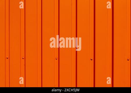 Profilierte Metallabdeckung, orange lackiert, auf einem temporären Büro einer Baustelle. Die Sonnenlichter tragen zur Struktur bei, indem sie eine Reihe von SHA erzeugen Stockfoto