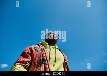 Ein hübscher afroamerikanischer Mann in stylischer Jacke schaut in den Himmel. Stockfoto