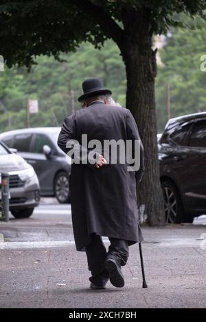 Ein generisches Foto eines älteren chassidischen jüdischen Mannes, der schwarz gekleidet ist und mit einem Stock geht. In Williamsburg, Brooklyn, New York. Stockfoto