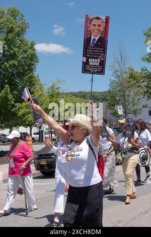 Ein Mitglied des Peekskill Seniors Club marschiert in der Junteenth Parade mit einer Flagge und einem Foto von Präsident Obama. In Peekskill, Juni 2024. Stockfoto