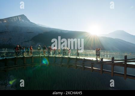 Columbia Icefield Skywalk. Touristen stehen auf der Aussichtsplattform mit Glasboden. Schneebedeckte Rocky Mountains im Hintergrund. Stockfoto