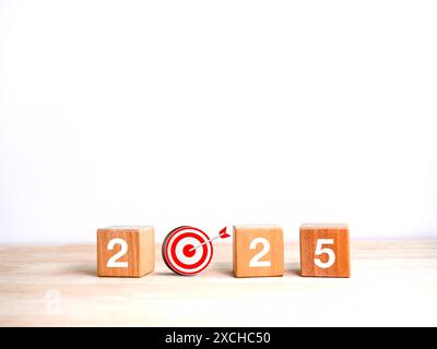 2025 Happy New Year Hintergrund Banner. Zahlen auf Holzwürfelblöcken mit 3D-Zieldart auf Holztisch und weißem Hintergrund mit Kopierraum. Busi Stockfoto