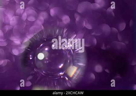 Violette Glitzerreflektionen durch eine Objektivkugel, auf schwarzem Hintergrund, weicher Fokus Stockfoto