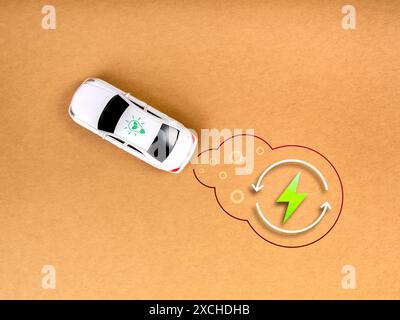 EV-Auto, Elektrobatterie-Ladefahrzeug mit nachhaltigem Entwicklungskonzept. Blick von oben auf ein weißes Spielzeugauto mit dem Symbol für die Energie auf dem umweltfreundlichen Bro Stockfoto