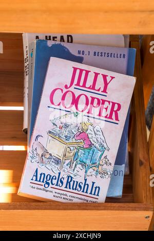 Ein Taschenbuch von Angels Rush in von Jilly Cooper. In einem Regal mit Büchern, die vor einem Second-Hand-Buchladen verkauft werden. Stockfoto