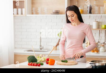 Junge Frau, die Gemüse auf Schneidebrett schneidet Stockfoto