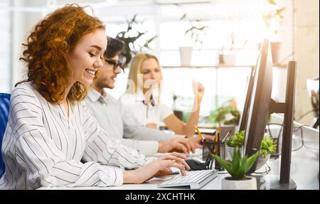 Gruppe junger Leute, die am Schreibtisch sitzen und an Computern arbeiten Stockfoto
