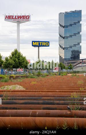 Berlin, Deutschland. Juni 2024. Rostige Stahlrohre liegen zwischen der Straße entlang der Ostbahn und dem Bahndamm kurz vor dem Ostbahnhof als Stützen. Das Bürogebäude des Edge East Side Tower (Amazon Tower) ist im Hintergrund zu sehen. Quelle: Soeren Stache/dpa/Alamy Live News Stockfoto