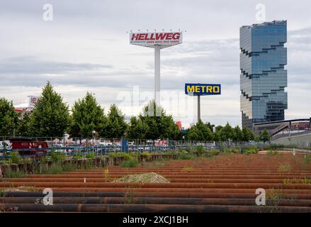 Berlin, Deutschland. Juni 2024. Rostige Stahlrohre liegen zwischen der Straße entlang der Ostbahn und dem Bahndamm kurz vor dem Ostbahnhof als Stützen. Das Bürogebäude des Edge East Side Tower (Amazon Tower) ist im Hintergrund zu sehen. Quelle: Soeren Stache/dpa/Alamy Live News Stockfoto