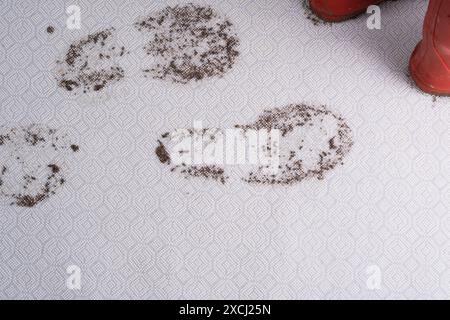 Matschiger Teppich. Schmutzige Fußabdrücke im feuchten Schlamm, rote Schuhe isoliert auf dem Hintergrund. Schmutzige Flecken im Alltag für Reinigungskonzept. Stockfoto