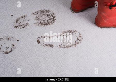 Matschiger Teppich. Schmutzige Fußabdrücke im feuchten Schlamm, rote Schuhe isoliert auf dem Hintergrund. Schmutzige Flecken im Alltag für Reinigungskonzept. Stockfoto