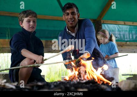 Premierminister Rishi Sunak toast Brot am offenen Feuer mit Kindern während eines Besuchs im Great Wood Farm Early Years Centre in Grantham in East Midlands, während er sich auf dem Wahlkampfpfad der General Election befindet. Bilddatum: Montag, 17. Juni 2024. Stockfoto