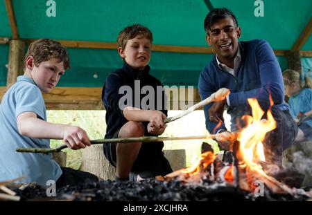 Premierminister Rishi Sunak toast Brot am offenen Feuer mit Kindern während eines Besuchs im Great Wood Farm Early Years Centre in Grantham in East Midlands, während er sich auf dem Wahlkampfpfad der General Election befindet. Bilddatum: Montag, 17. Juni 2024. Stockfoto