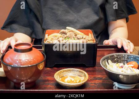 Asiatische Frau, die bereit ist, japanisches Essen zu essen, gegrilltes Rindfleisch mit Reis, Gyu Donburi in bento-Box Stockfoto
