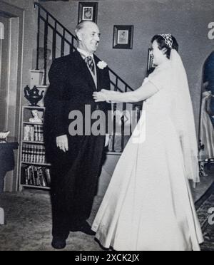 Junge Frau im Hochzeitskleid mit ihrem Vater, die sich auf ihre Hochzeit in den USA der 1950er vorbereitet Stockfoto