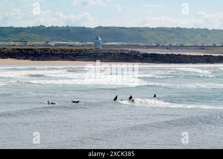 Surfer am Coney Beach, mit Trecco Bay, dem Küstenwachturm und Merthyr Mawr im Hintergrund. Porthcawl, Großbritannien. Juni 2024 Stockfoto