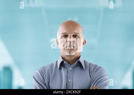 Selbstbewusster, reifer Ingenieur in High-Tech-Büros, umgeben von Arbeitern und Angestellten. Konzentrieren Sie sich auf Problemlösung und strategisches Denken Stockfoto