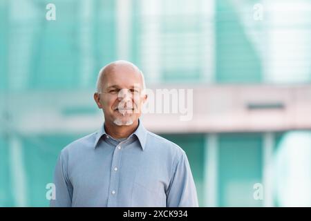 Ein selbstbewusster Geschäftsmann vor einem modernen Bürogebäude strahlt Professionalität und Führungsposition im urbanen Stadtbild aus und symbolisiert Fortschritt und Innovation Stockfoto